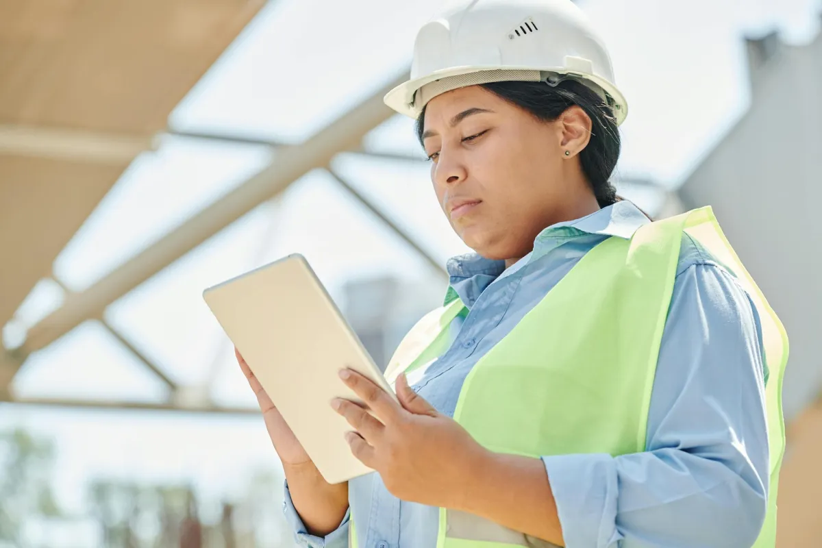 Construction worker using tablet on building site for AI-powered project management