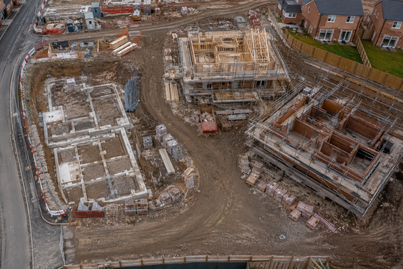Aerial drone view of UK residential construction site showing multiple plots at different stages